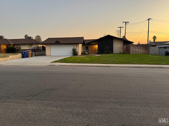 ranch-style house featuring a garage and a lawn