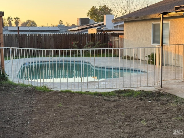 pool at dusk with a patio and central air condition unit