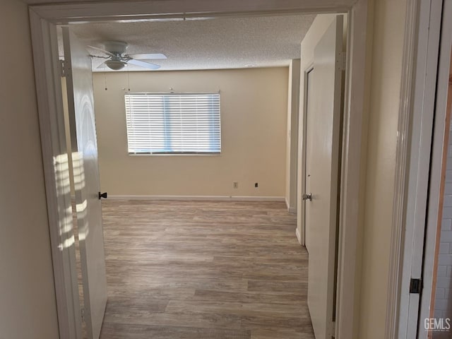 interior space featuring ceiling fan, a textured ceiling, and light hardwood / wood-style floors