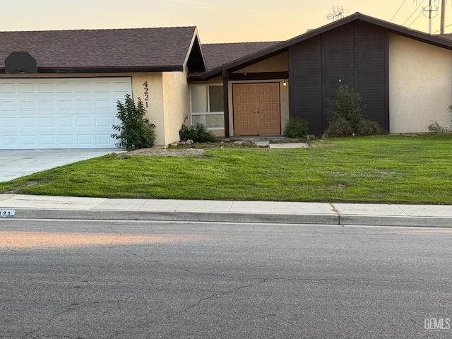 ranch-style home with a garage and a yard