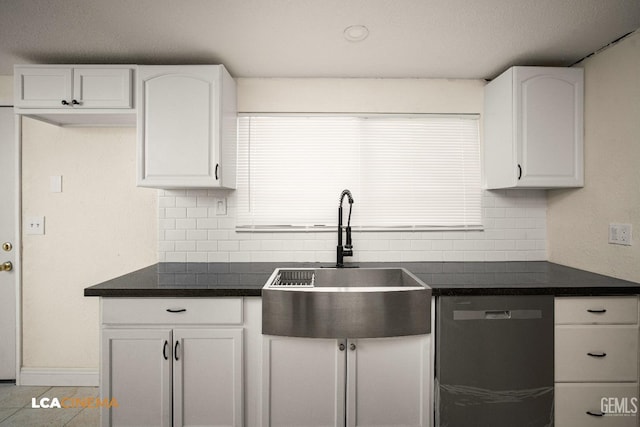 kitchen featuring decorative backsplash, stainless steel dishwasher, sink, light tile patterned floors, and white cabinets