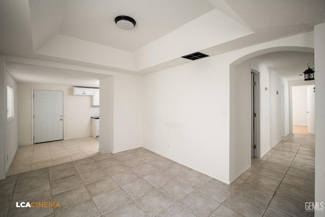 unfurnished room with light tile patterned flooring and a raised ceiling