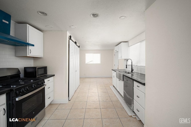 kitchen featuring appliances with stainless steel finishes, tasteful backsplash, sink, wall chimney range hood, and white cabinetry