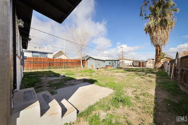 view of yard with an outdoor structure, a fenced backyard, a storage shed, and a patio area