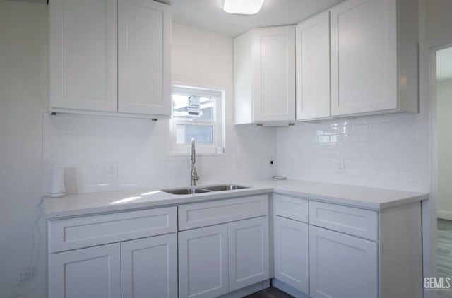 kitchen featuring light countertops, white cabinets, backsplash, and a sink