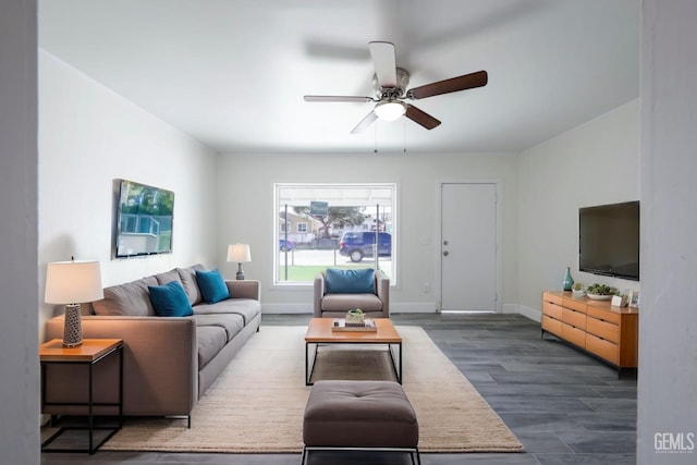 living room featuring baseboards, ceiling fan, and dark wood-style flooring