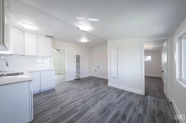 kitchen with visible vents, a sink, light countertops, white cabinets, and dark wood-style flooring