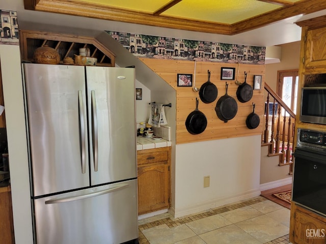 kitchen featuring stainless steel refrigerator, tile countertops, oven, and light tile patterned flooring