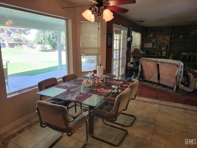 dining area with a brick fireplace, tile patterned floors, and ceiling fan