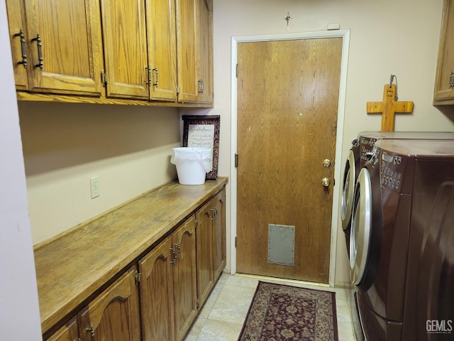 clothes washing area featuring separate washer and dryer and cabinets