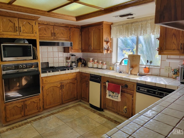 kitchen featuring stainless steel appliances, tile counters, sink, and backsplash