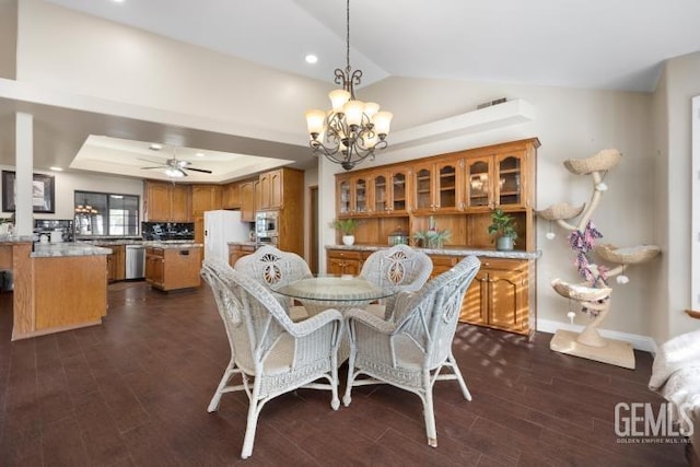 dining area featuring a tray ceiling, lofted ceiling, dark hardwood / wood-style floors, and ceiling fan with notable chandelier