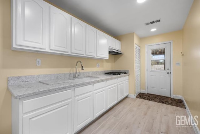 kitchen featuring light hardwood / wood-style flooring, white cabinetry, and light stone counters