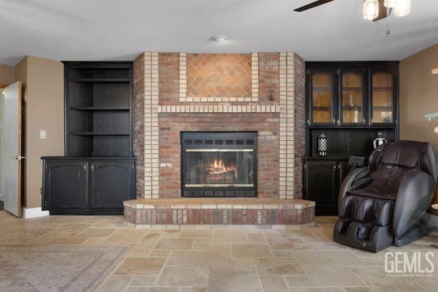 unfurnished living room with ceiling fan and a brick fireplace