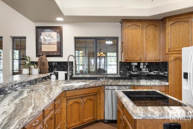 kitchen with dishwasher, sink, light stone counters, backsplash, and black electric cooktop