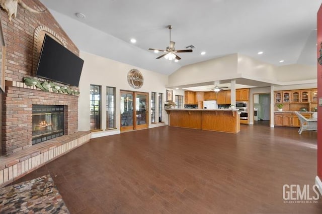 unfurnished living room with lofted ceiling, french doors, a brick fireplace, ceiling fan, and dark hardwood / wood-style flooring