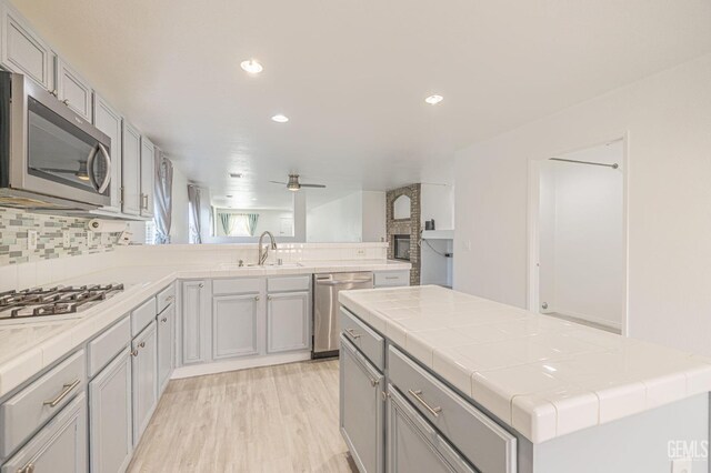 kitchen featuring ceiling fan, a center island, stainless steel appliances, tasteful backsplash, and light hardwood / wood-style flooring