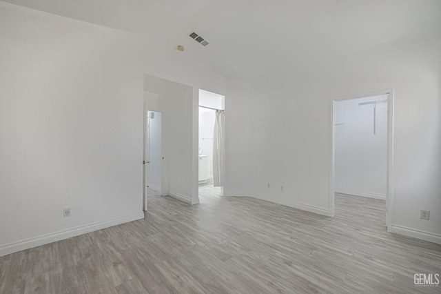 empty room featuring vaulted ceiling and light wood-type flooring