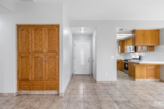 kitchen with decorative backsplash, appliances with stainless steel finishes, and light tile patterned floors