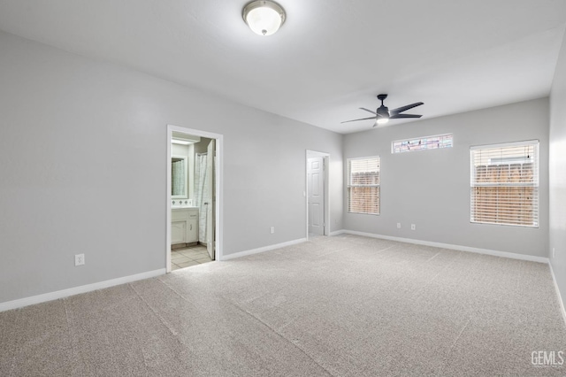 unfurnished bedroom featuring ceiling fan, light colored carpet, multiple windows, and ensuite bath