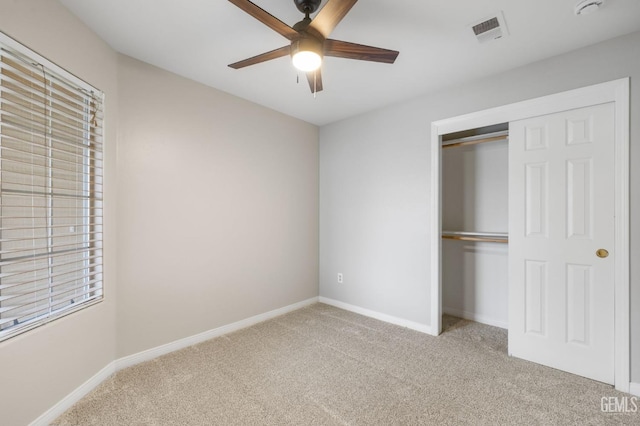 unfurnished bedroom with ceiling fan, light colored carpet, and a closet