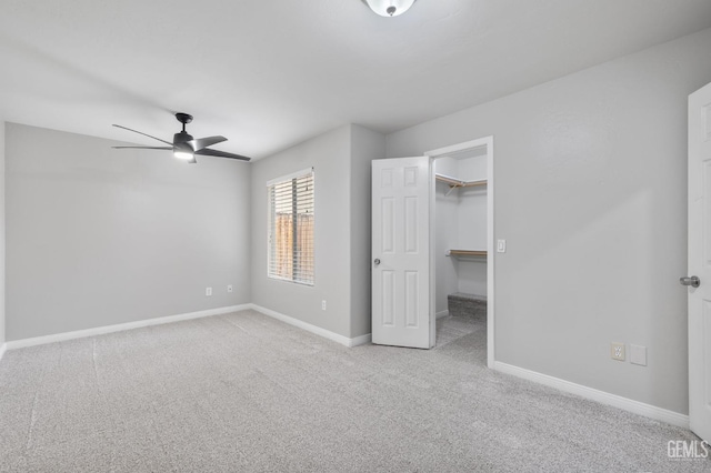 unfurnished bedroom featuring ceiling fan, a walk in closet, light carpet, and a closet