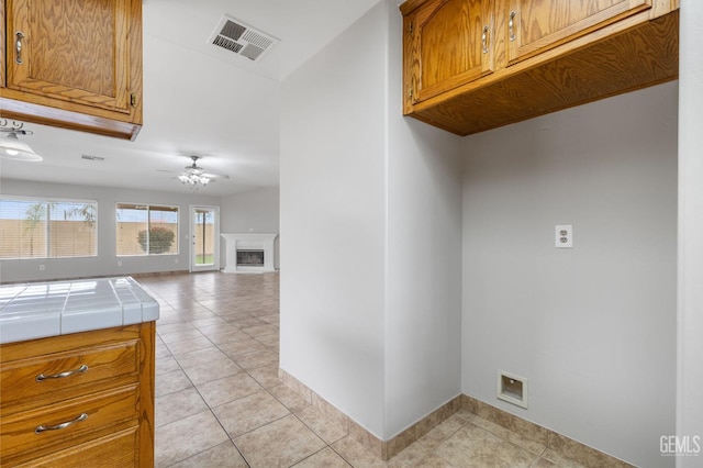 laundry area with ceiling fan and light tile patterned floors