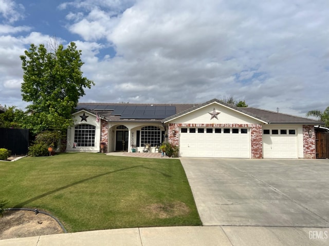 ranch-style house with a front lawn, covered porch, roof mounted solar panels, concrete driveway, and an attached garage