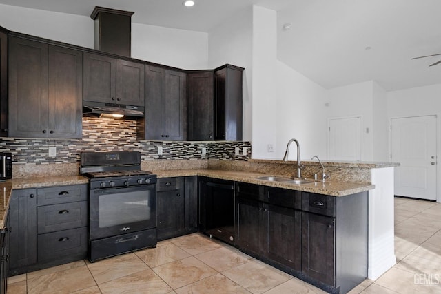 kitchen with light stone countertops, dark brown cabinets, under cabinet range hood, a sink, and gas stove