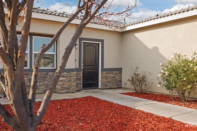 property entrance featuring stone siding and stucco siding