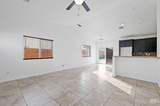 unfurnished living room with vaulted ceiling, ceiling fan with notable chandelier, visible vents, and baseboards