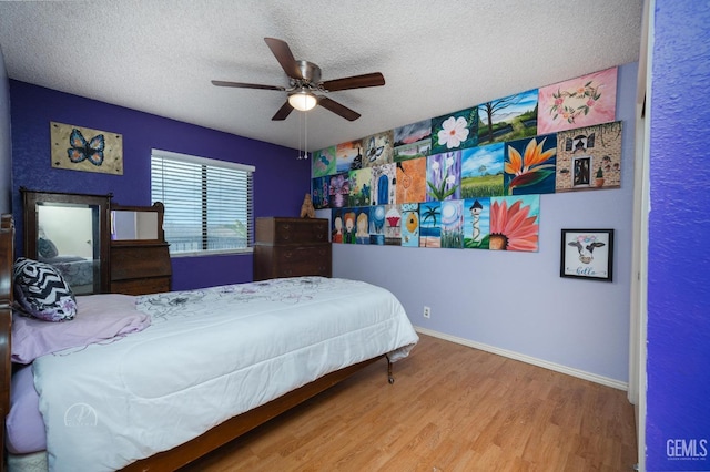 bedroom featuring hardwood / wood-style floors, a textured ceiling, and ceiling fan