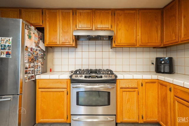 kitchen featuring tasteful backsplash, stainless steel appliances, and tile counters