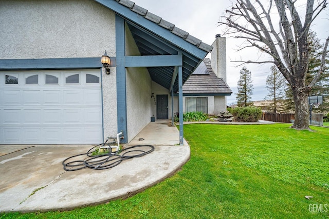 view of front of home featuring stucco siding, a garage, a chimney, and a front lawn