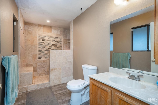 bathroom featuring vanity, tiled shower, and toilet