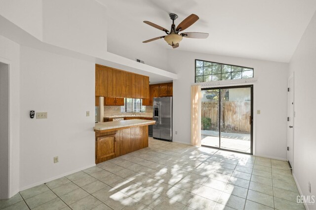 7205 Bandolero Way, Bakersfield, CA 93308 - kitchen with stainless steel fridge, a peninsula, brown cabinets, high vaulted ceiling, and ceiling fan