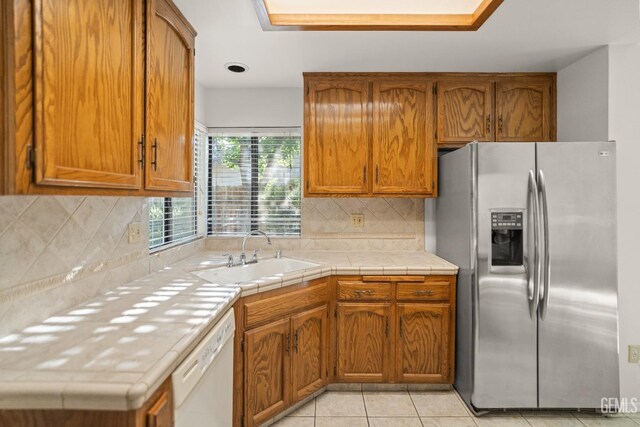 7205 Bandolero Way, Bakersfield, CA 93308 - kitchen featuring stainless steel refrigerator with ice dispenser, a sink, white dishwasher, brown cabinets, and tasteful backsplash
