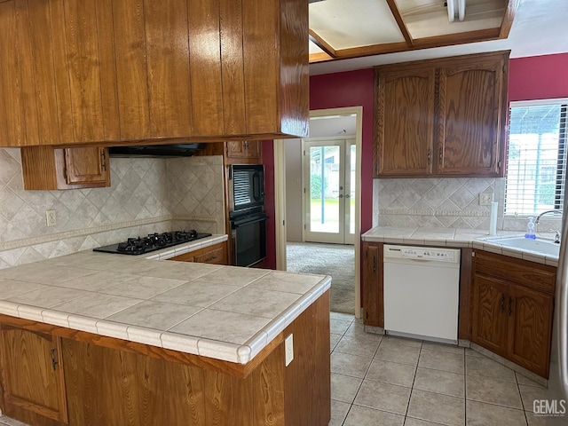 kitchen featuring sink, tile counters, black appliances, and plenty of natural light