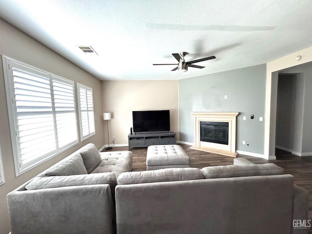 10315 Paradiso Way, Bakersfield, CA 93306 - living area with dark wood-type flooring, baseboards, a ceiling fan, a glass covered fireplace, and a textured ceiling