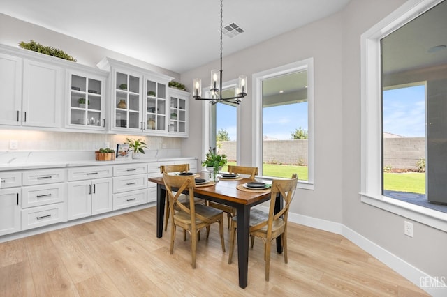 dining area with light wood-type flooring and a notable chandelier