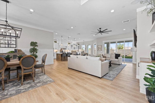 living room with ceiling fan with notable chandelier and light wood-type flooring