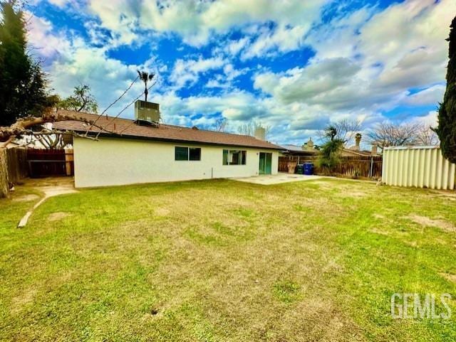 rear view of property featuring cooling unit, a patio area, and a lawn