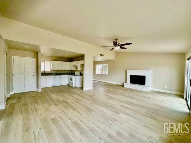 unfurnished living room with a brick fireplace, light hardwood / wood-style floors, and ceiling fan