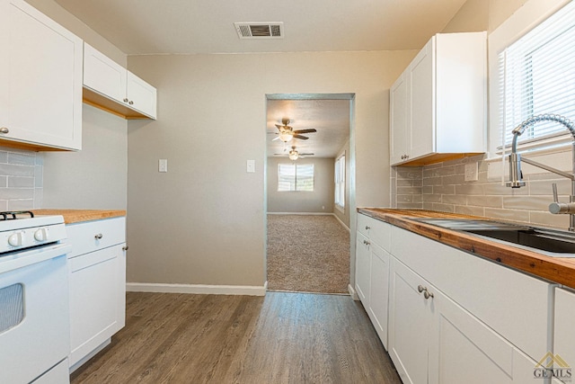 kitchen with butcher block countertops, decorative backsplash, sink, and white range