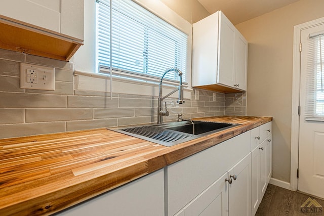 kitchen with wooden counters, sink, decorative backsplash, dark hardwood / wood-style floors, and white cabinetry