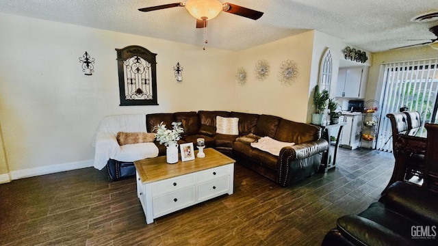 living area with visible vents, a ceiling fan, a textured ceiling, dark wood finished floors, and baseboards