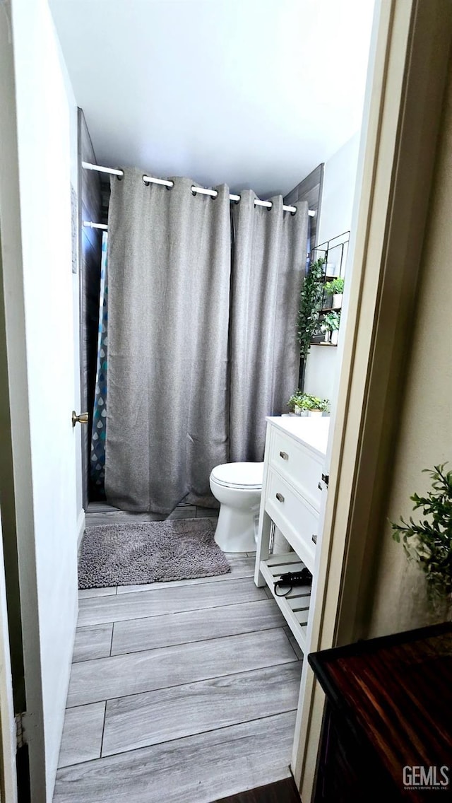 full bath with vanity, toilet, a shower with shower curtain, and wood finished floors