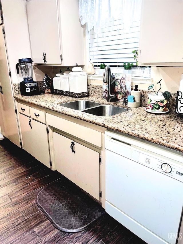 kitchen with dark wood-type flooring, a sink, white cabinets, white dishwasher, and light stone countertops