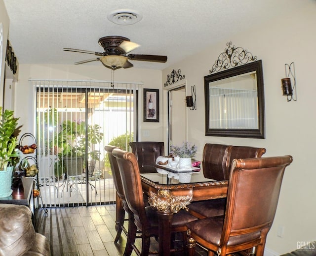 dining room featuring ceiling fan, wood finished floors, visible vents, and a textured ceiling