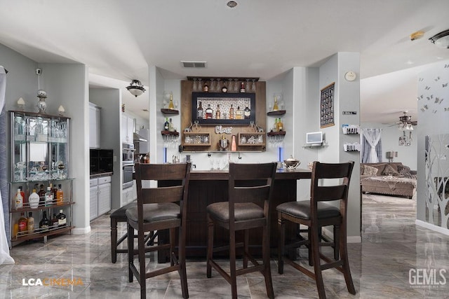 11703 Revolution Rd, Bakersfield, CA 93312 - indoor bar featuring marble tiled floors, ceiling fan, and stainless steel double oven